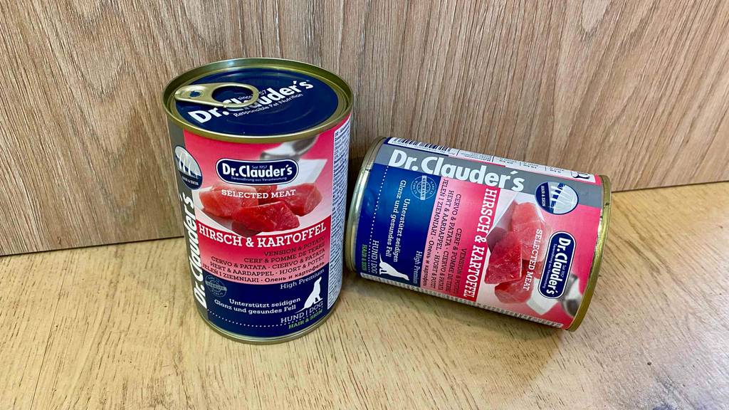 Zwei Dosen eines getesteten Nassfutters für Hunde befinden sich in einem Holzregal.