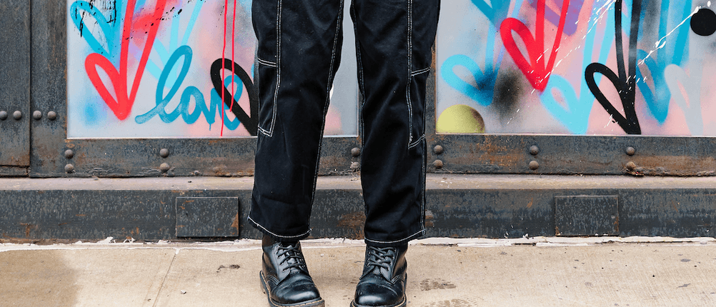 Dr. Martens für Damen im Test: Frau trägt schwarze Docs vor einer Wand voller Graffiti.