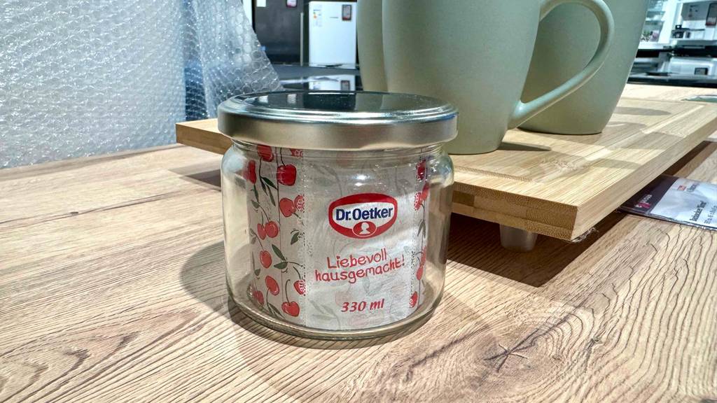 Einmachgläser getestet: Das Dr.-Oetker-Glas mit Schraubverschluss steht auf einer Holzoberfläche neben mehreren Kaffeetassen.