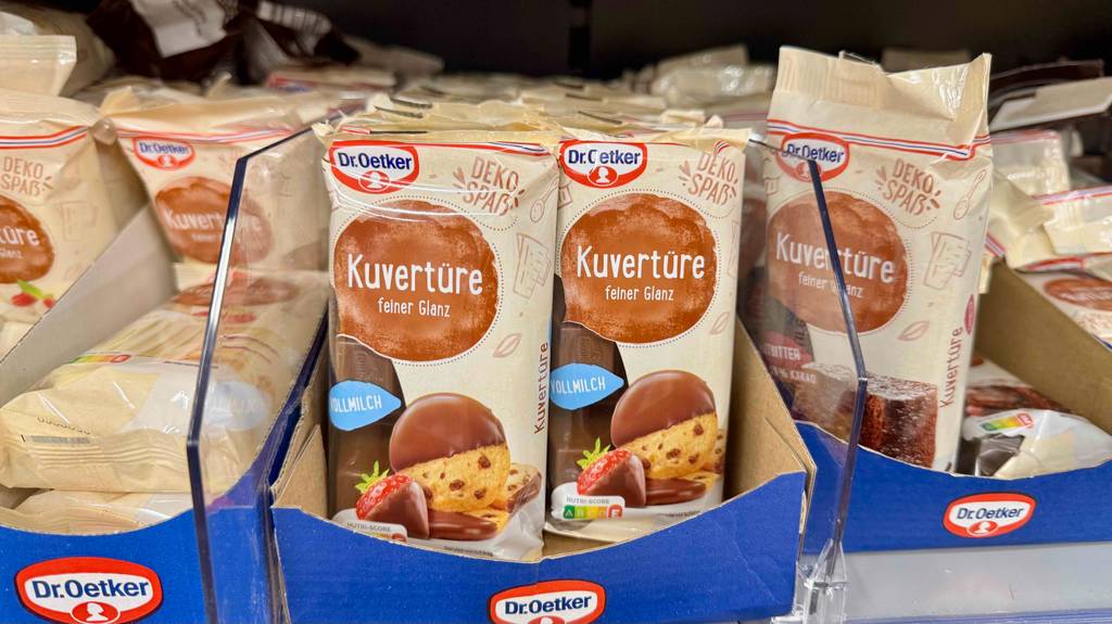Mehrere Packungen mit getesteter Kuvertüre von Dr. Oetker stehen nebeneinander im Verkaufsregal.