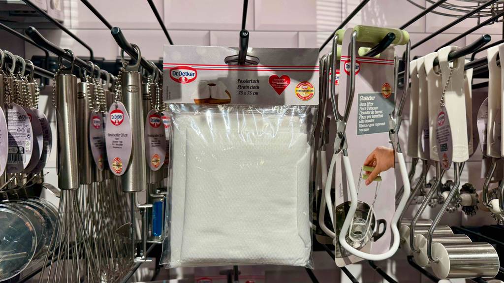 Passiertuch im Test: Mehrere Packungen hängen zwischen Haushaltshelfern in einem Hängeregal.
