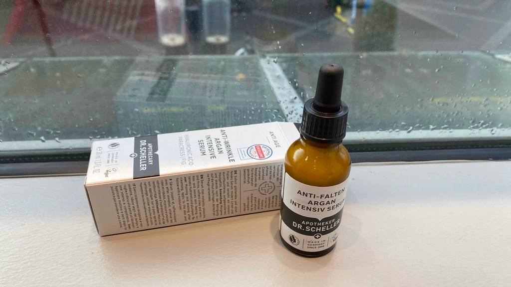 Anti-Falten-Serum im Test der Marke Dr. Scheller befindet sich vor einem Schaufenster im Inneren eines Drogeriemarkts.