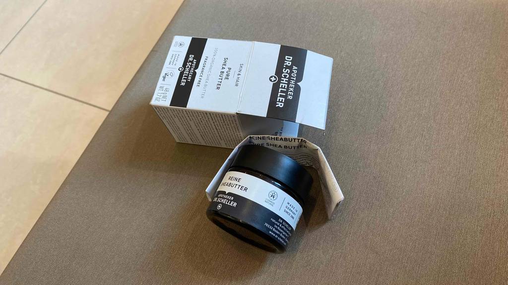 Über einem Gläschen getestete Bio Sheabutter liegen der Beipackzettel und die Originalverpackung.