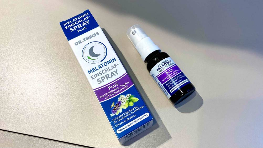 Melatonin-Spray-Test: Neben der Originalverpackung liegt eine Flasche quer auf einer hellen Fläche.