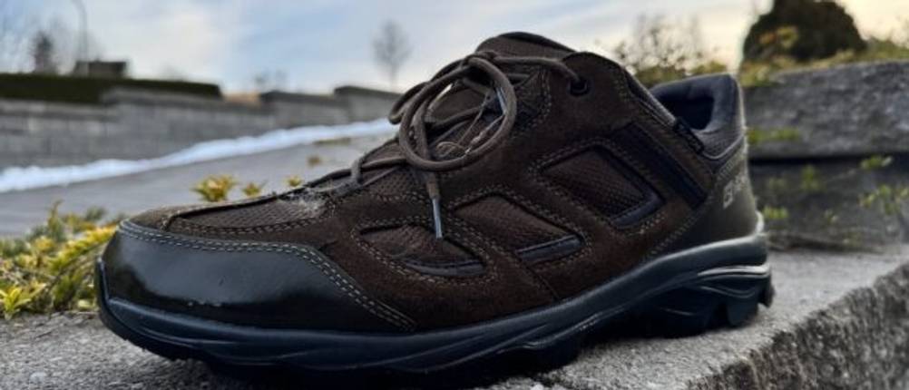 Glänzender Schuh nach dem Imprägnieren auf einer Steinmauer