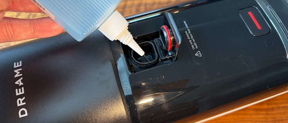 Eine Hand gibt eine Flüssigkeit in den Dreame H14 Pro