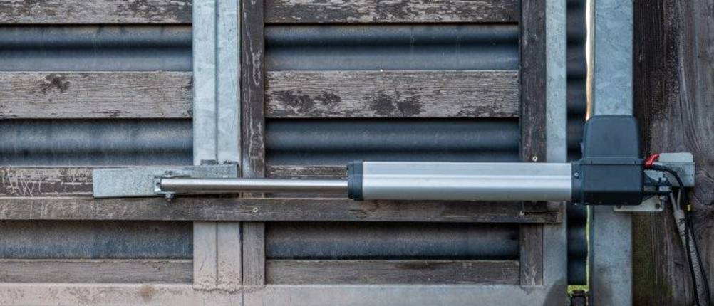 Drehtorantrieb im Test: Ein Drehtorantrieb ist an einem Holztor montiert.