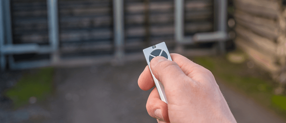 Drehtorantrieb im Test: Eine Hand hält einen Funksender vor einem Gartentor.