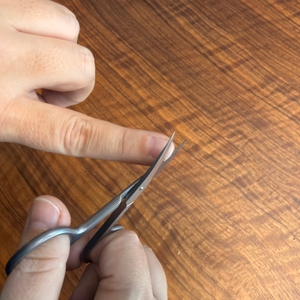 Eine Person schneidet mit der Drei-Schwerter-Nagelschere AE 1912 einen Fingernagel.