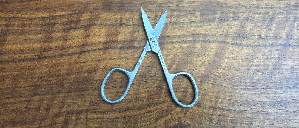 Die Drei-Schwerter-Nagelschere AE 1912 liegt geöffnet auf einem Tisch.