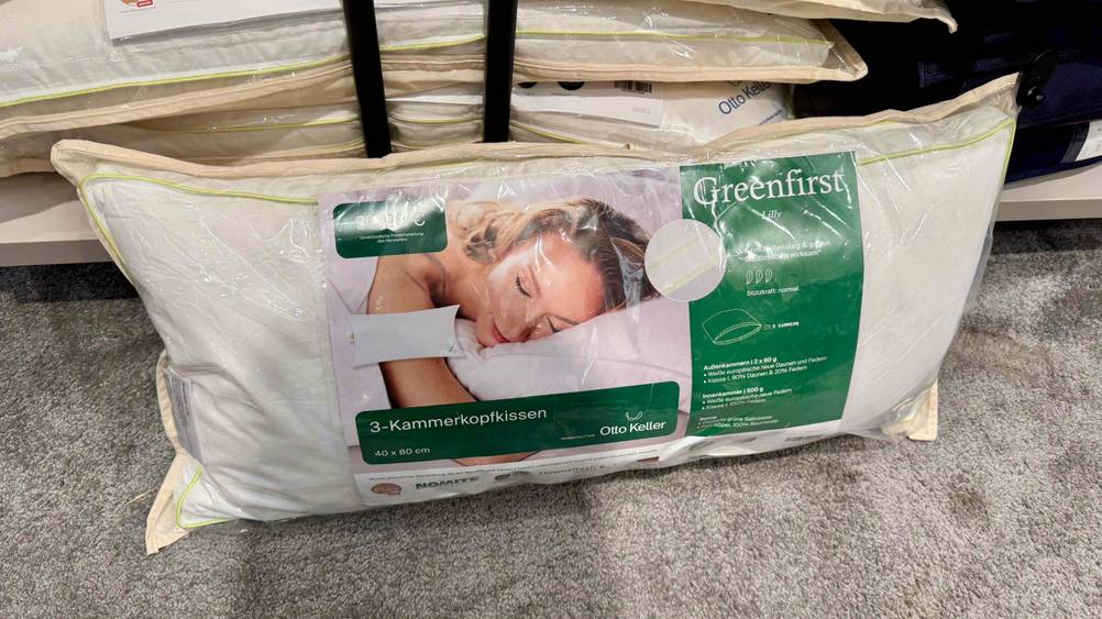 Dreikammer-Kopfkissen im Test: Ein verpacktes Kissen steht auf einem Teppich.