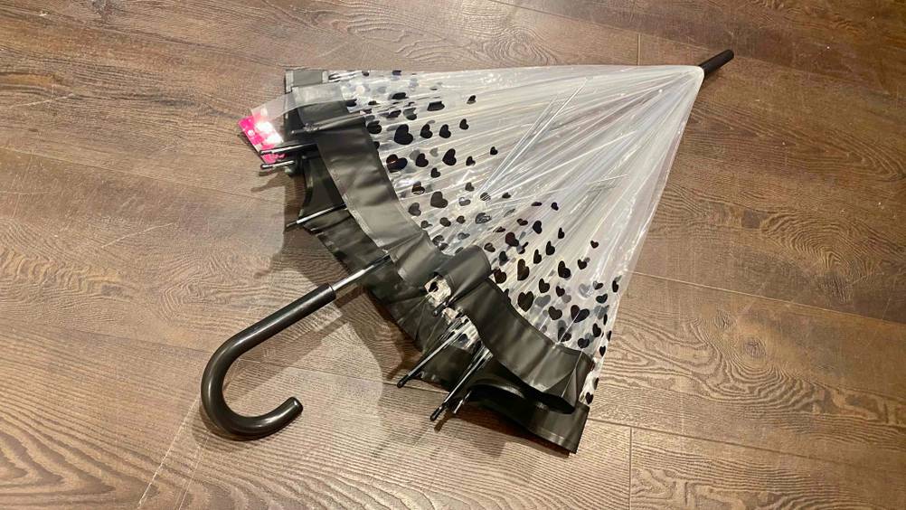 Durchsichtiger Regenschirm getestet: Ein geschlossenes Produkt liegt auf einem Holzboden.