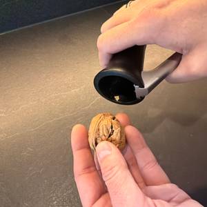 Eine Hand hält eine geknackte Walnuss aus dem Drosselmeyer-Nussknacker ‎DR03 fest