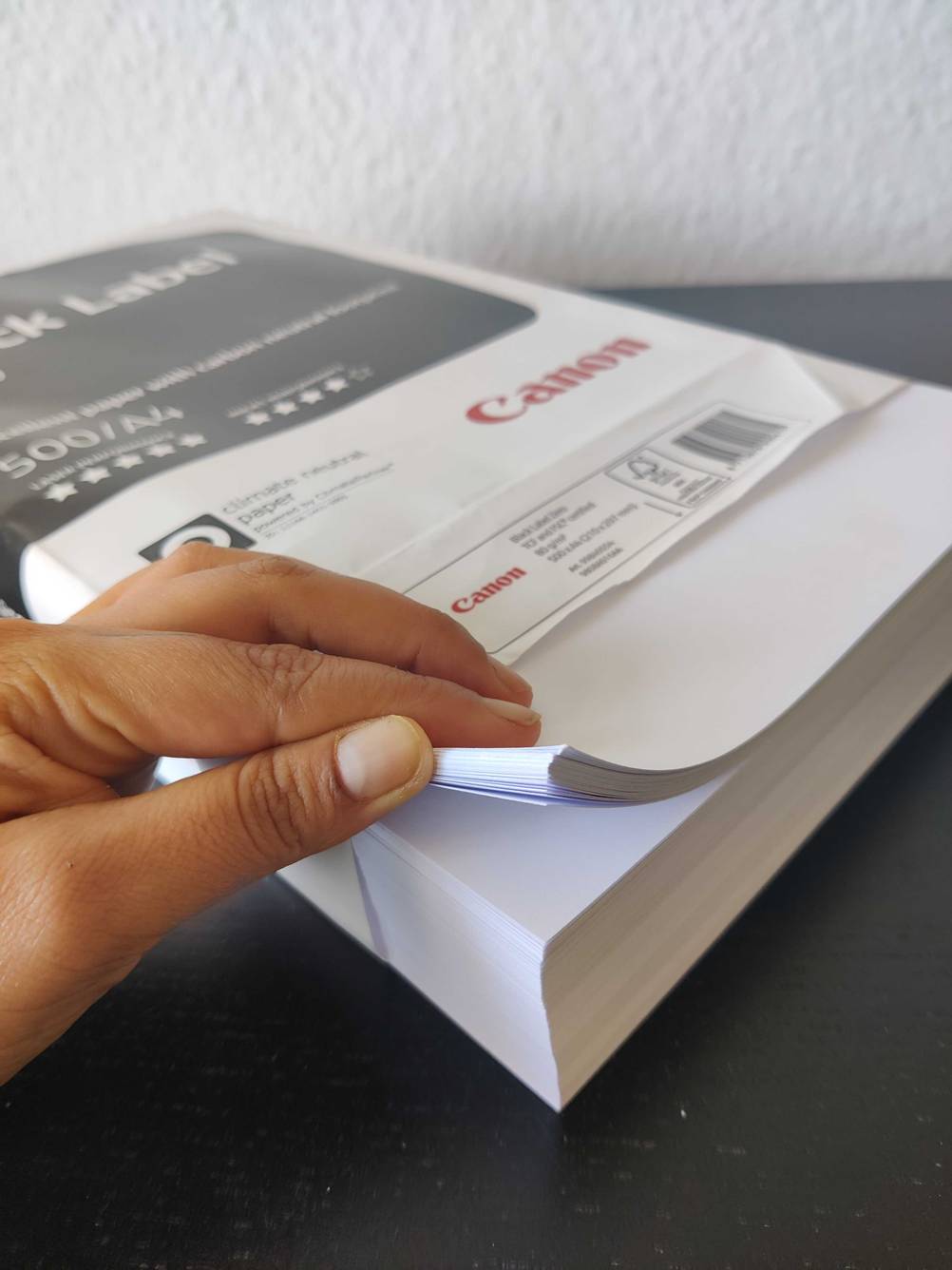 Eine Hand hält einen Stapel des getesteten Druckerpapiers zwischen den Fingern.
