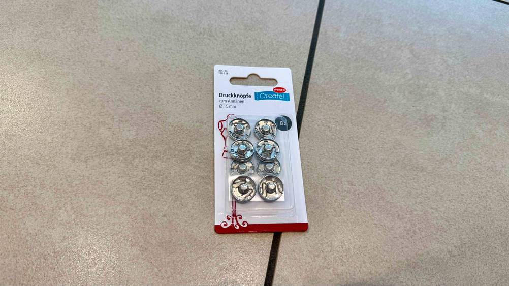 Getestet: Eine Packung Druckknöpfe liegt auf einem Fließenboden.