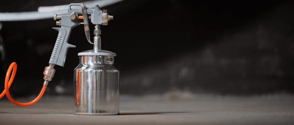 Druckluft-Set im Test: Eine Druckbecherpistole mit Druckluftschlauch angeschlossen.