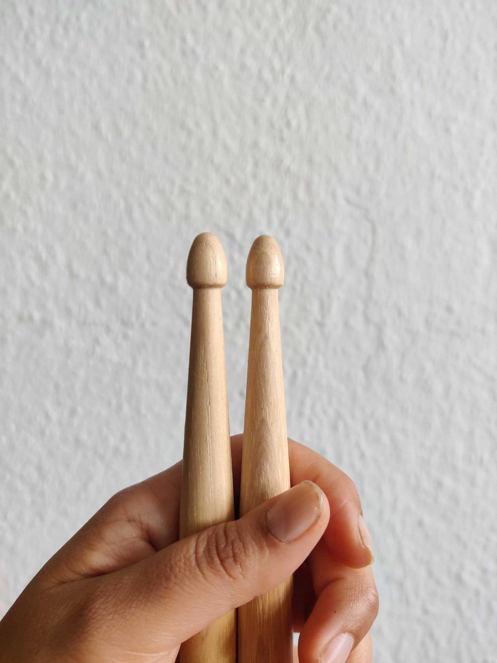 Eine Hand hält die Drumsticks im Test vor eine hellen Wand.