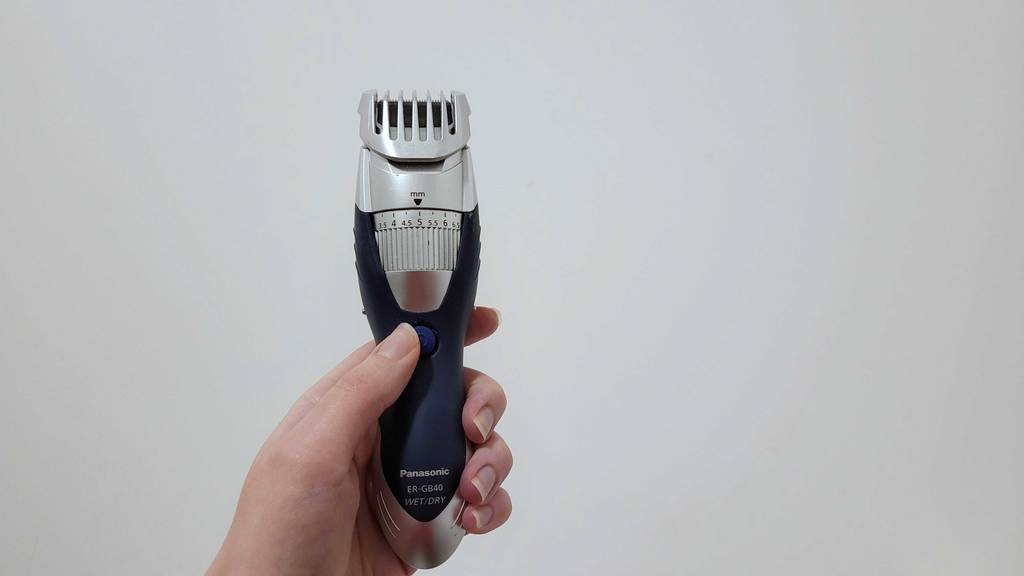 Bartschneider im Test: Eine Hand hält ein Gerät und drückt mit dem Daumen auf die Powertaste.