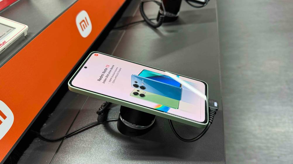 Ein Dual-SIM-Smartphone im Test von der Seite auf einem Ständer in einer Ausstellung mit Sicherung.