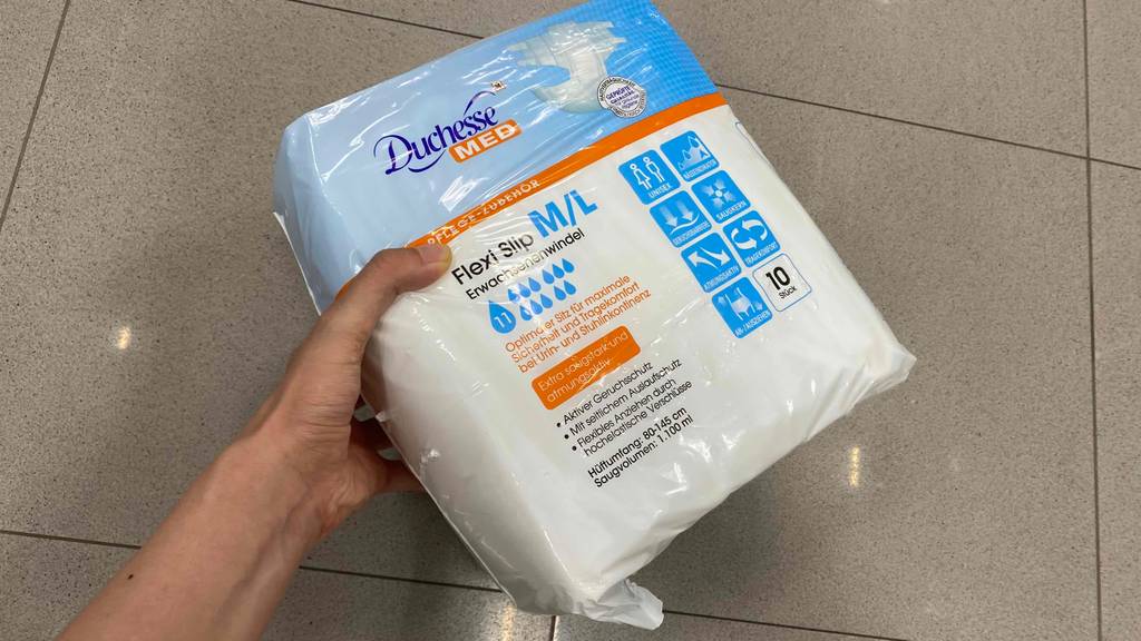Hand hält eine Packung mit 10 Stück Duchesse-Windeln-Erwachsene für den Test hoch.