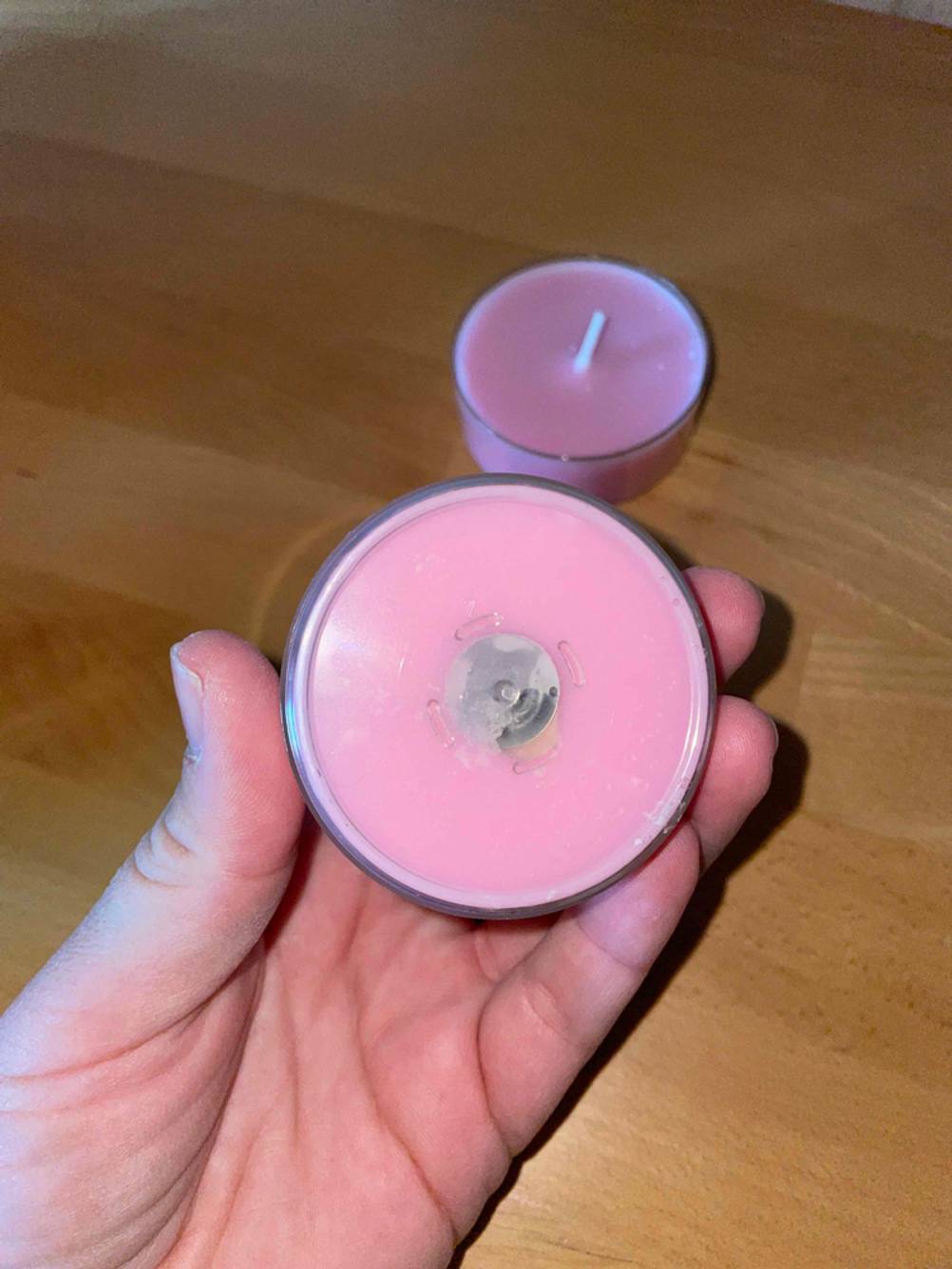 Eine Hand hält den Boden einer getesteten Duftkerze nach oben.