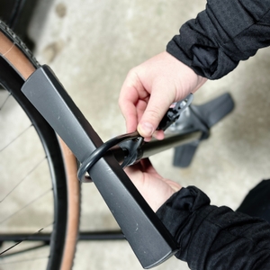 Ein Nutzer verstaut den Schlauch der Dunlop 17049 am oberen Griff der Standpumpe. Der Schlauch wird durch eine Halterung geführt.