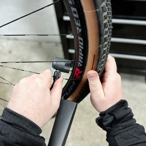 Ein Nutzer befestigt den Pumpenkopf der Dunlop 17049 am Sclaverand-Ventil eines Fahrrads. Die Felge gehört zu einem Gravelbike.