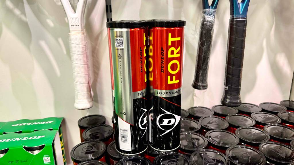 Im Test: Zwei Dosen Dunlop-Tennisbälle stehen auf anderen Dosen vor Tennisschlägern.
