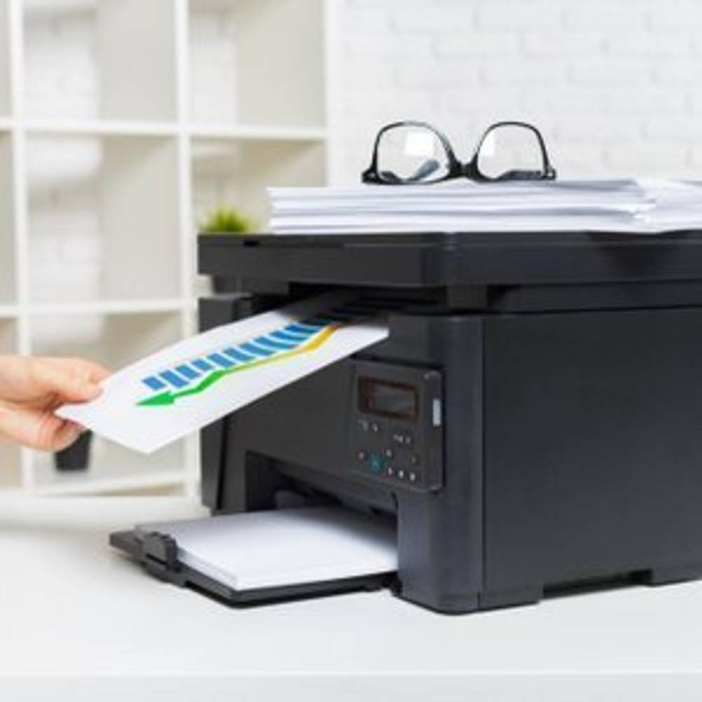 Ein schwarzer Drucker, der ein Blatt mit einer Grafik ausgibt, das von einem Mann entnommen wird