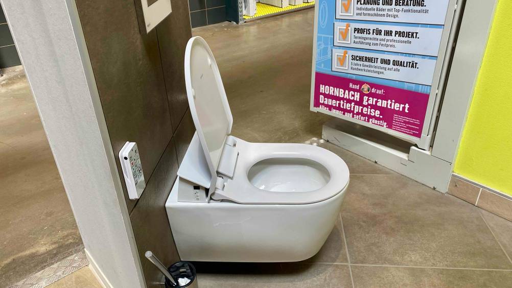 Im Test: Ein Dusch-WC von der Seite mit geöffnetem Deckel in einer Ausstellung eines Baumarktes.