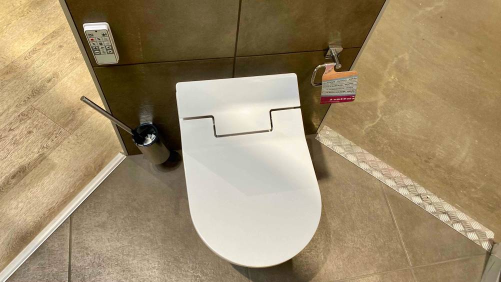 Dusch-WC getestet: Ein Produkt von oben mit geschlossenem Deckel, daneben eine Klobürste.