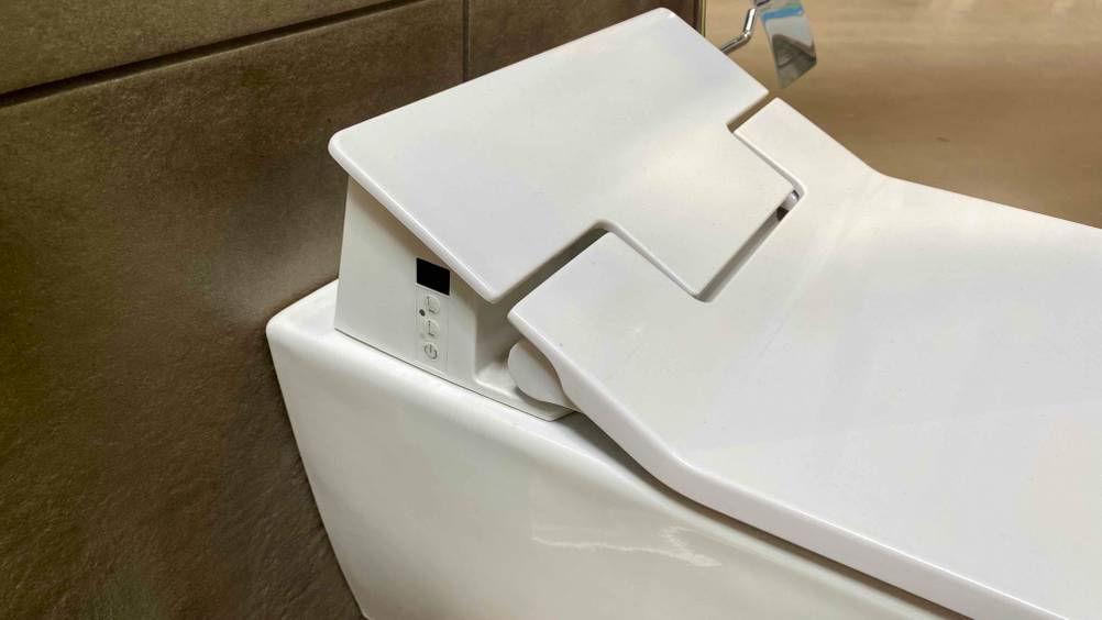 Nahaufnahme des Klappmechanismus eines getesteten Dusch-WC mit Bedienelementen.