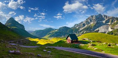 Landschaftsbild mit Bergen im Hintergrund, einer Straße und einer kleinen Hütte im Durmitor-Nationalpark.