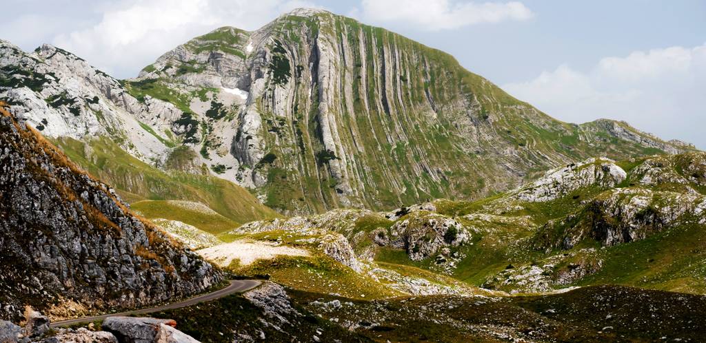 Berge mit deutlich erkennbaren Formationen des Gesteins, die die Entstehung des Bergs darlegen. Im Vordergrund rechts sieht mein eine Straße.