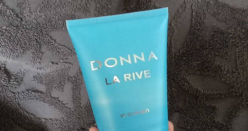 Nahaufnahme des Logos auf einer Tube des getesteten Duschgels für Damen vor einem dunklen Handtuch.