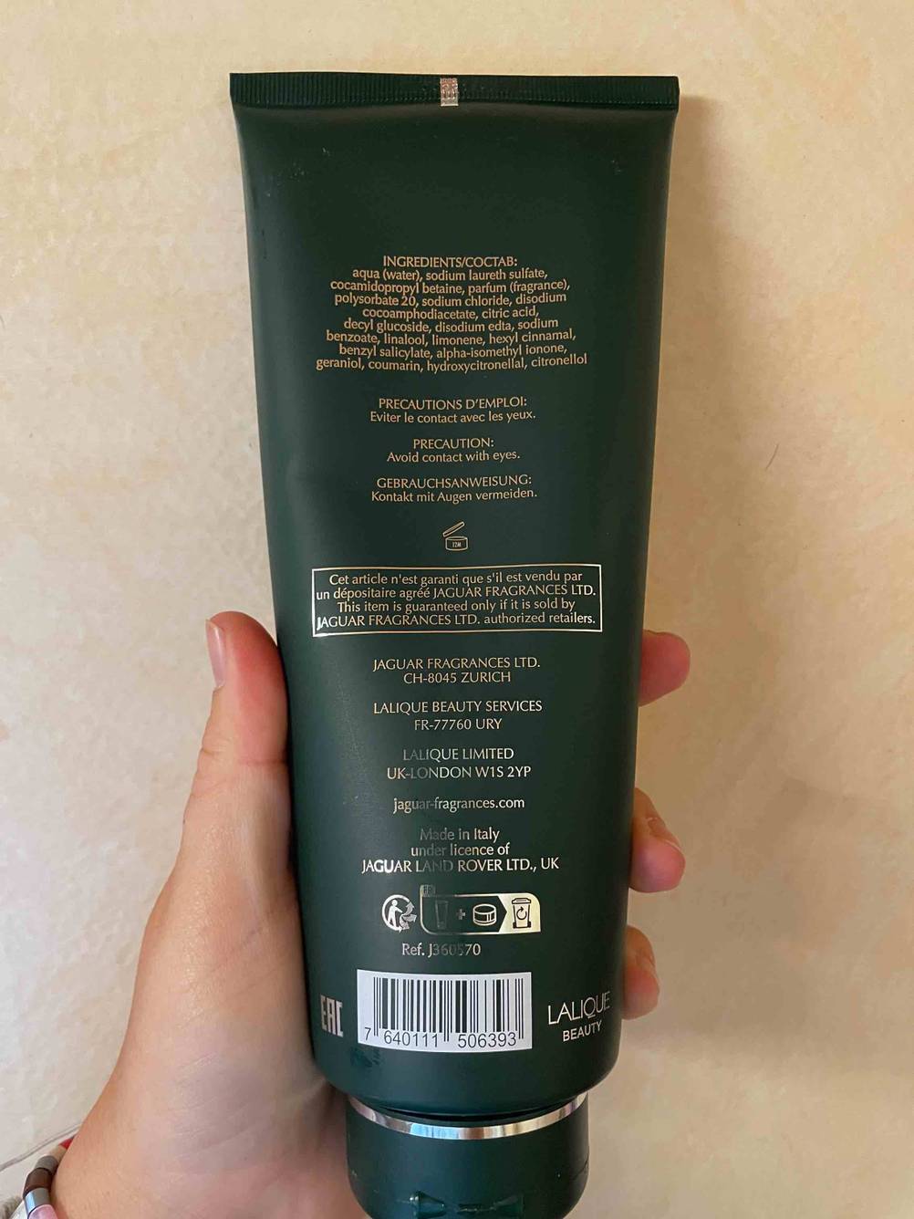 Im Test: Eine Hand hält die Rückseite eines Duschgels für Herren vor eine beige Wand.