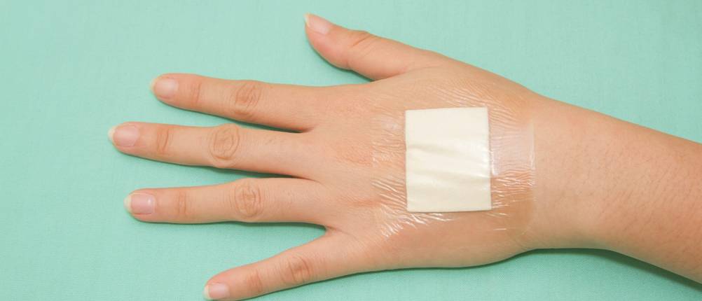 Eine Hand mit einem Duschpflaster auf dem Handrücken