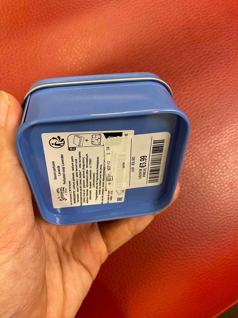 Rückseite einer originalverpackten Duschseife vor einer roten Fläche.