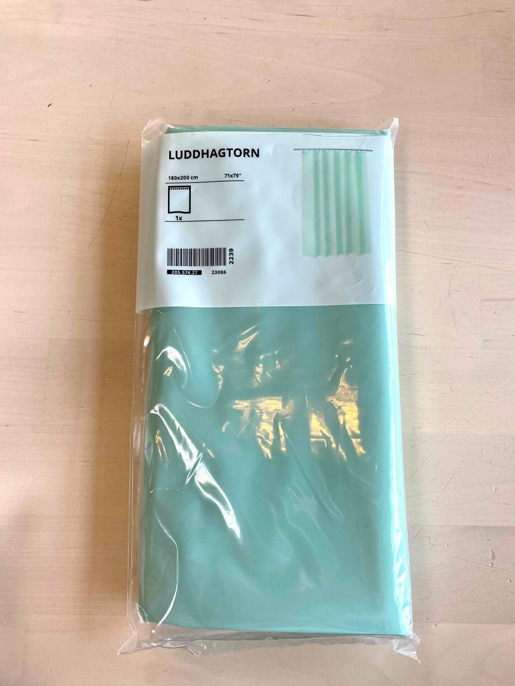 Duschvorhang getestet: Ein verpackter Vorhang in blau auf einer Holzfläche.