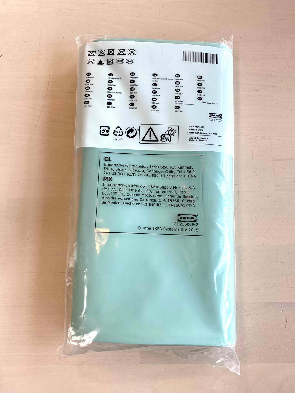 Rückseite eines originalverpackten Duschvorhanges auf einer Holzfläche.