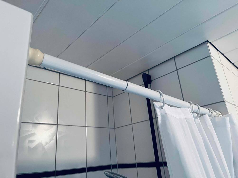 Getestete Duschvorhangstange befindet sich in hellem Badezimmer.