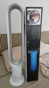 Getesteter leiser Ventilator von Dyson steht neben der Originalverpackung auf einem beigefarbenen Bettbezug.