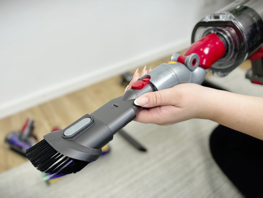 Eine Hand hält die Kombibürste des Dyson V15 Detect in Nahaufnahme. Der Aufsatz ist aufgesteckt und verriegelt.