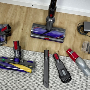 Das Zubehör des Dyson V15 Detect ist auf dem Boden ausgebreitet. Zu sehen sind Düsen, Bürsten, Adapter und Ladegerät.