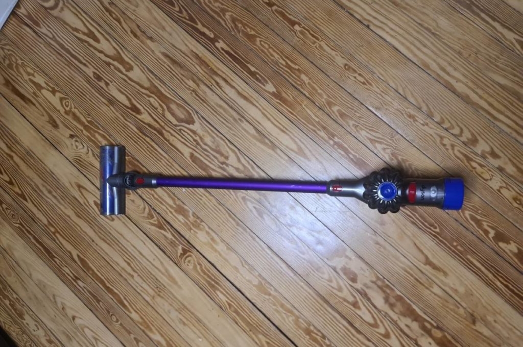 Handstaubsauger-Test: ein violettfarbenes Modell der Marke Dyson auf einem Holzboden.