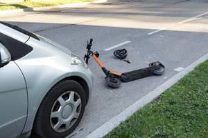 E-Scooter-Versicherungen getestet: Ein E-Roller liegt nach einem Unfall vor einem einem Auto.