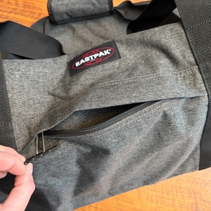 Eine Hand öffnet ein Fach an der Außenseite der Eastpak TERMINAL-+-Reisetasche