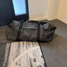 Die Eastpak TERMINAL-+-Reisetasche steht auf einem Fliesenboden