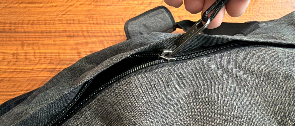 Eine Hand öffnet einen Reißverschluss an der Eastpak TERMINAL-+-Reisetasche