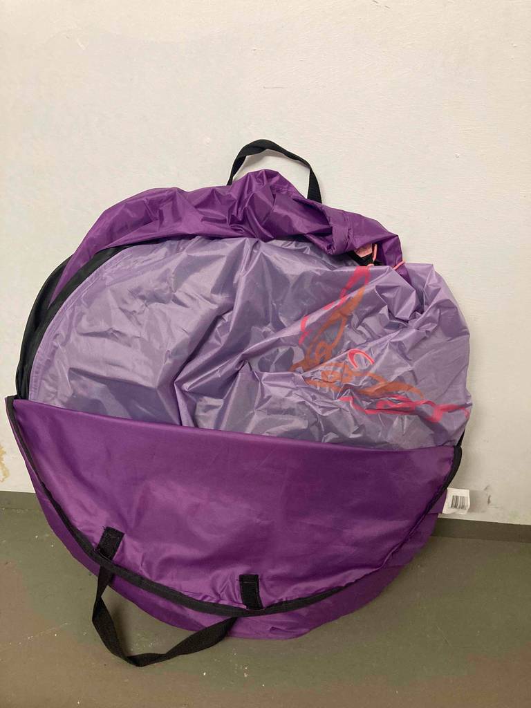 Easy Camp Antic Einmannzelt im Test lehnt in seiner violettfarbigen Transporttasche an einer weißen Wand.